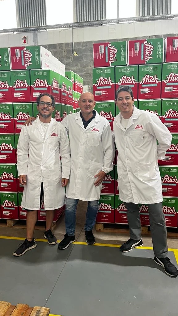 Gastón Arcucci, Nicolás Olleac y Manuel Pucheta en la planta de FRUCH, entre cajas de chips de manzana